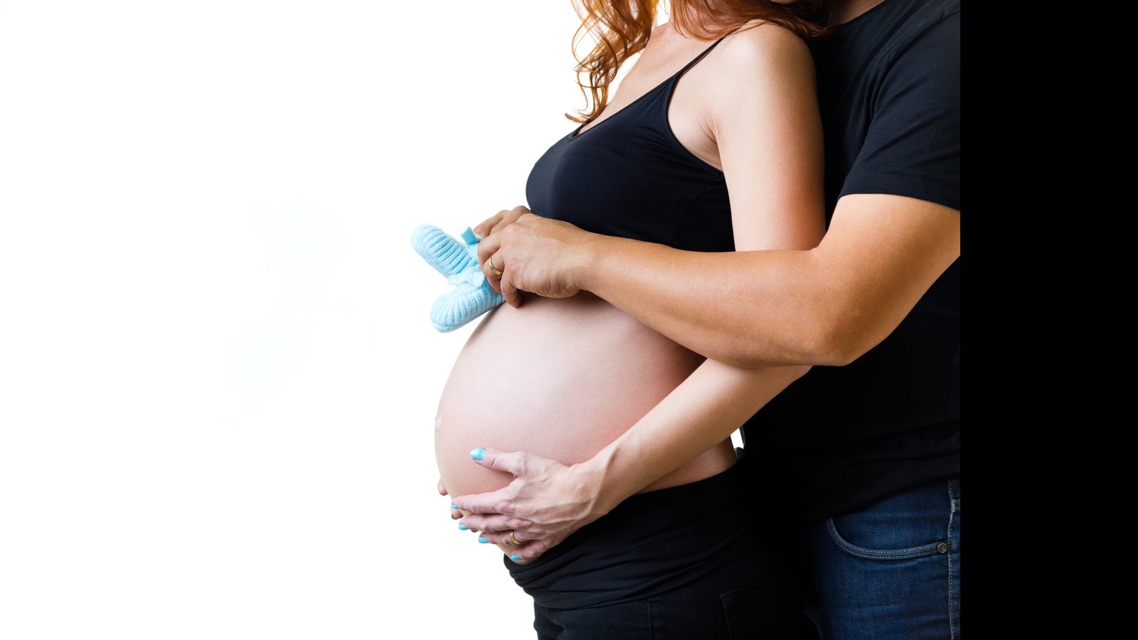 Futura mamá sosteniendo unos patucos de bebé sobre su barriga