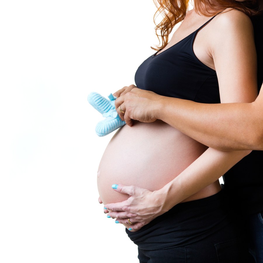 Futura mamá sosteniendo unos patucos de bebé sobre su barriga
